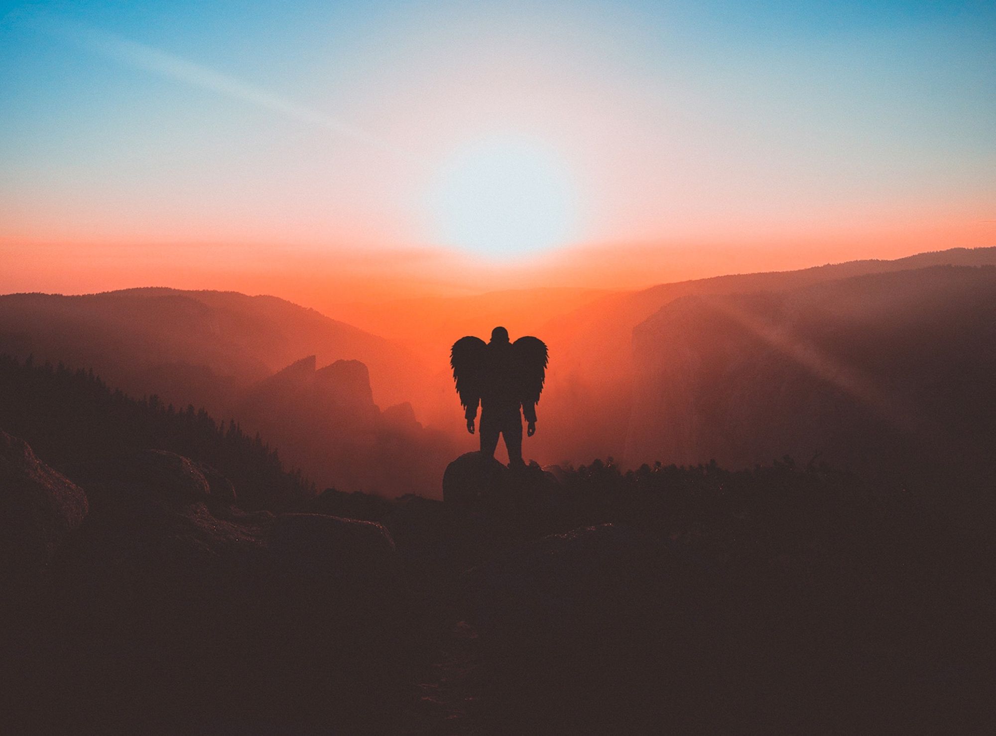 man-with-wings-standing-on-brown-mountain-peak-2043837-2