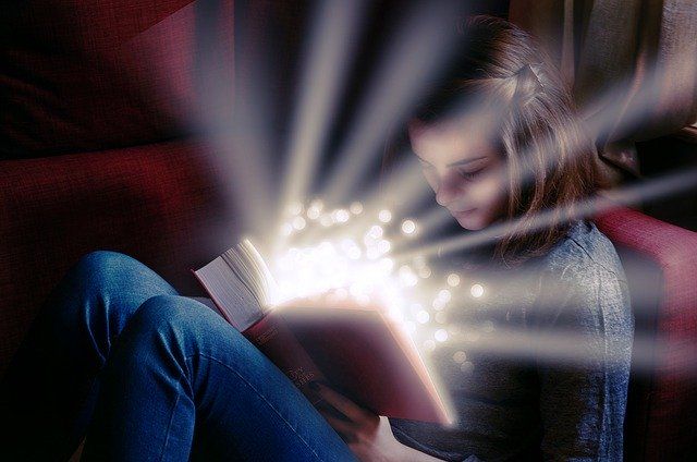 girl-sitting-on-couch-reading-a-red-book-emanating-rays-of-light-small