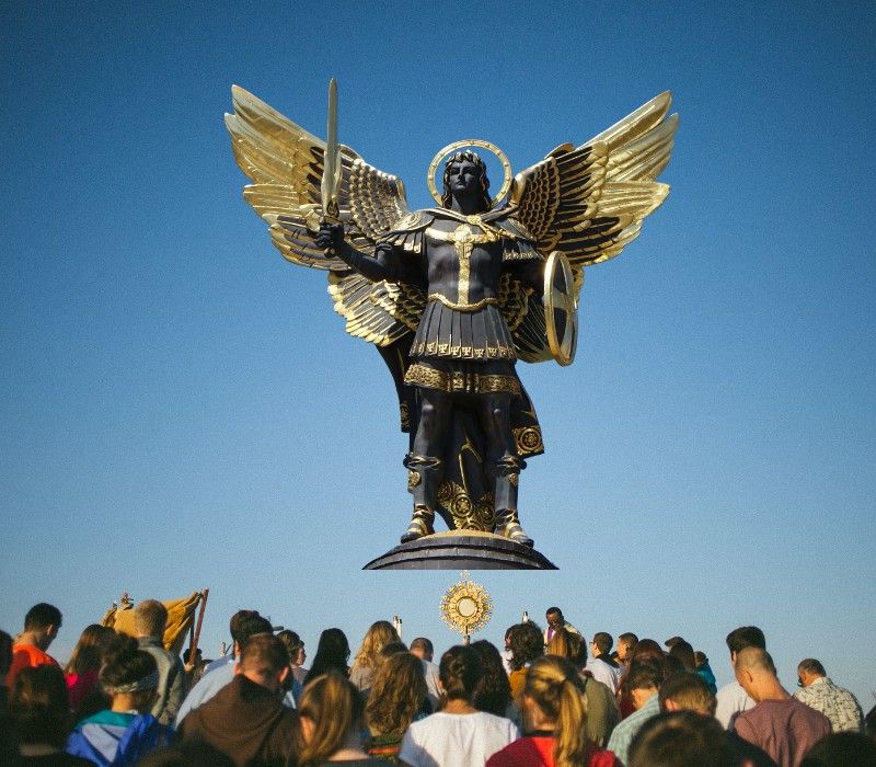 statue of archangel michael standing over a gathered crowd of believers