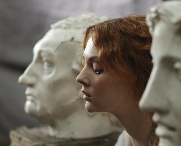 Profile image of a short-haired young woman looking sad sitting between two white half-length busts